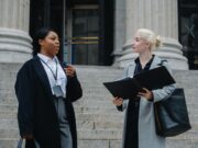 elegant-diverse-female-business-partners-with-documents-talking-on-street