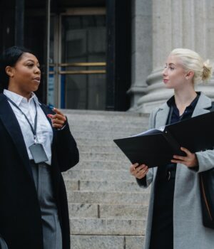 elegant-diverse-female-business-partners-with-documents-talking-on-street