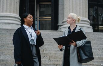 elegant-diverse-female-business-partners-with-documents-talking-on-street