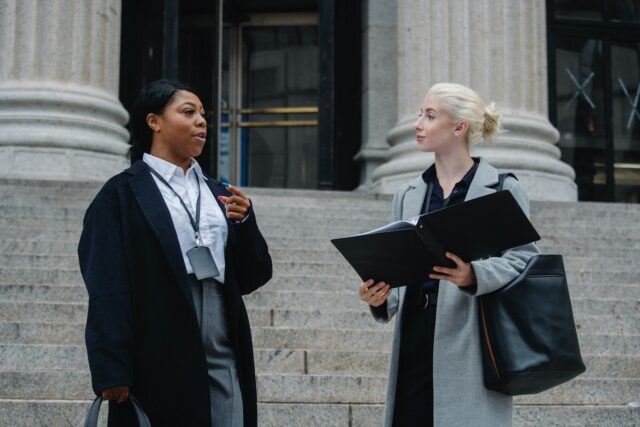 elegant-diverse-female-business-partners-with-documents-talking-on-street